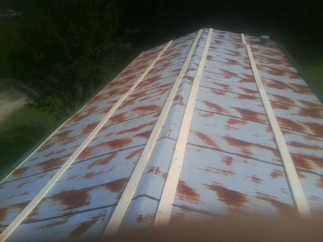 Rusted metal roof panels with new wood purlins before replacement — Storm Damage Roof Repair in New Knoxville by Roofing Brothers