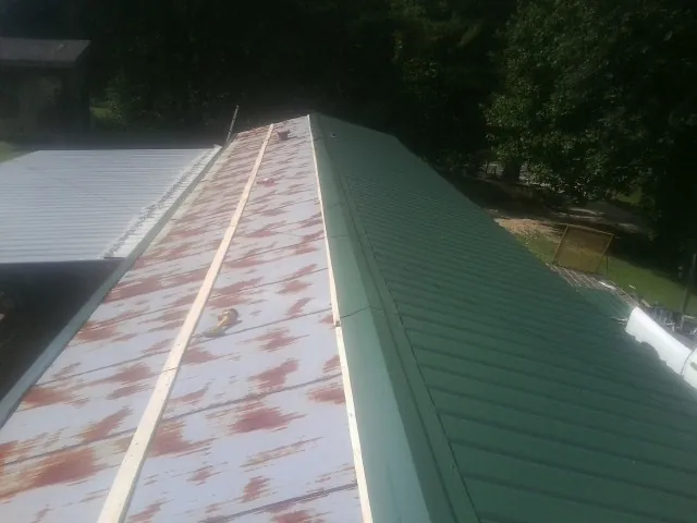 Old rusted panels beside newly installed green metal roofing — Wind Damage Roof Repair by Roofing Brothers in New Knoxville