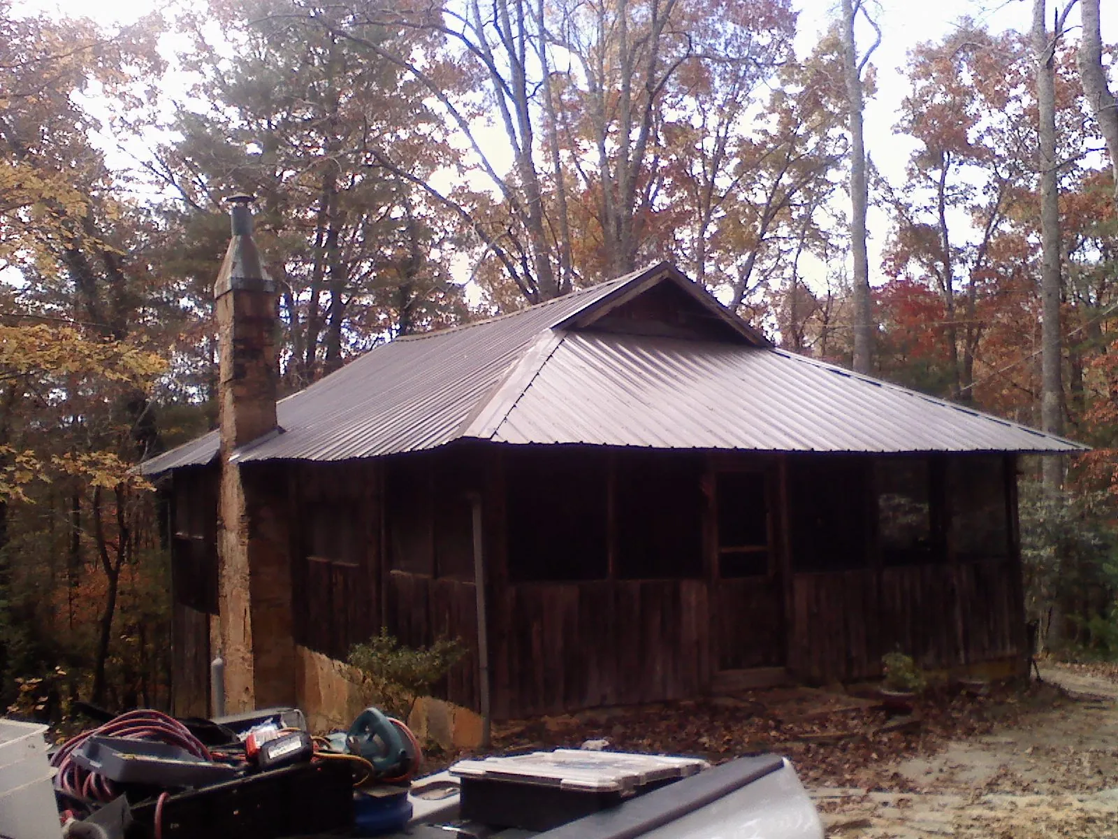 Brown metal hip roof on an old cabin with a stone chimney in New Knoxville