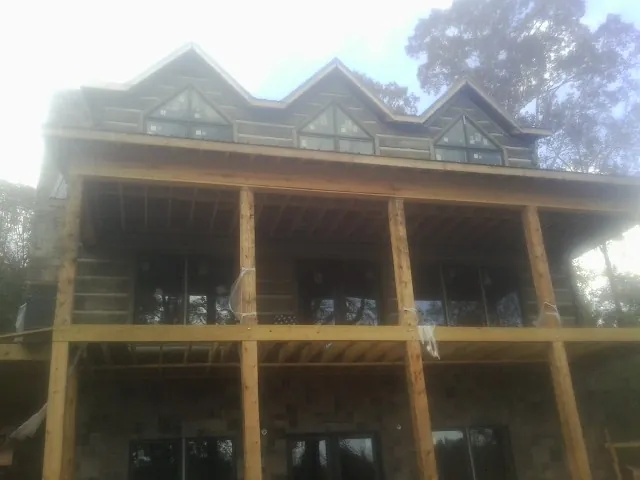 Dormers and porch framing on a large log home under construction — Roof Coating work by our crew in New Knoxville