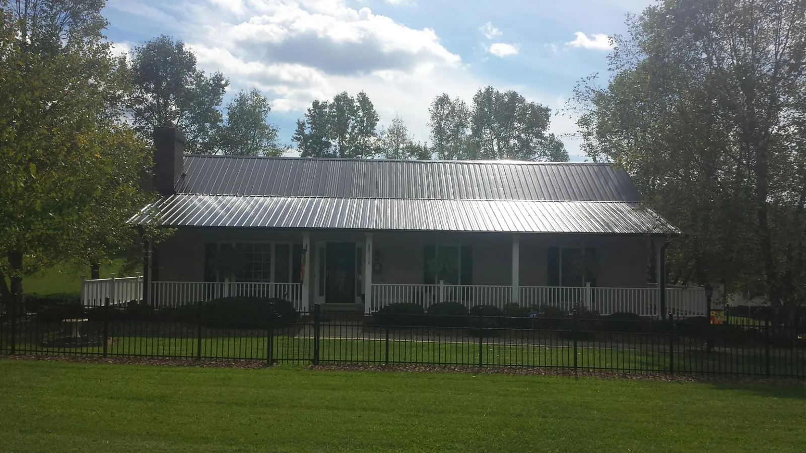 Gray metal roof on a brick ranch with a full width front porch — Gutter Guard Installation work by our crew in New Knoxville