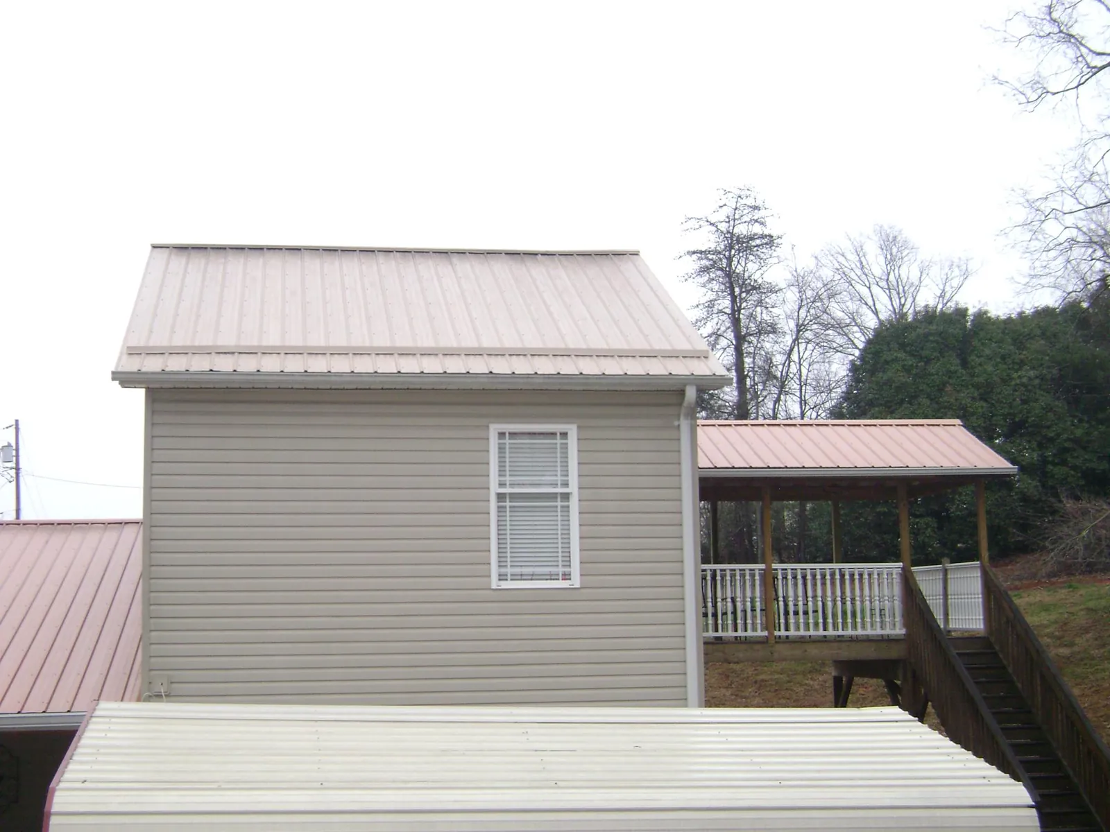 Tan metal roofs on a two story addition and attached porch, from a Roof Replacement job in New Knoxville