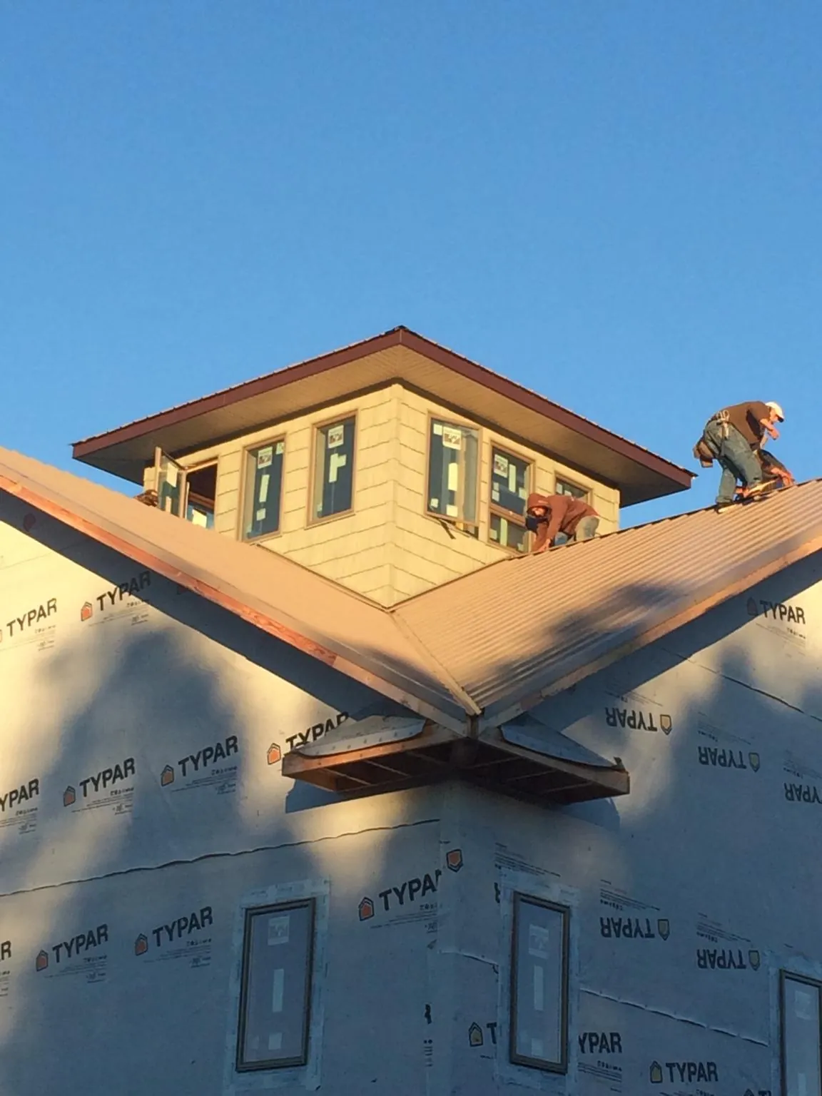 Roofers working around a rooftop cupola on a new metal roof at sunset — Roof Waterproofing in New Knoxville by Roofing Brothers